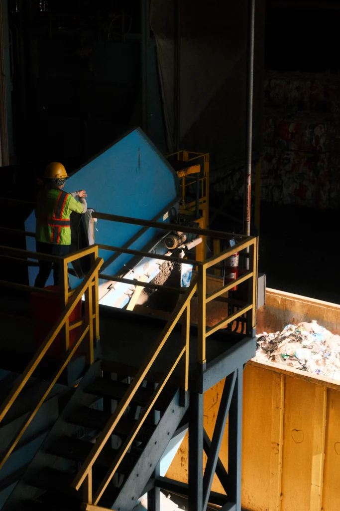 Operario alimenta material en la banda de clasificación de la planta